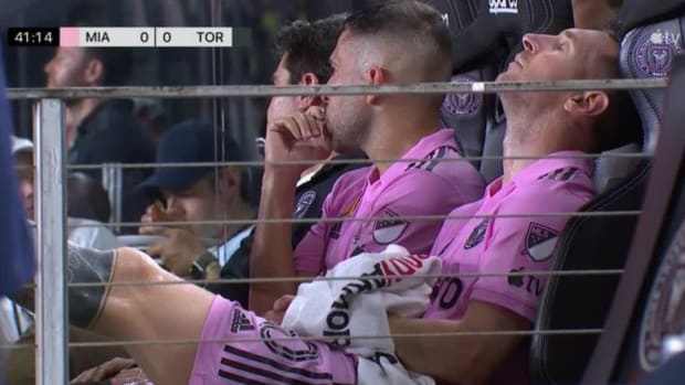 Lionel Messi pictured (right) sat on the Inter Miami bench with his left foot raised after being substituted off during a game against Toronto FC in September 2023